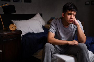 Fototapeta na wymiar Depressed young man suffering from insomnia sitting in bed..