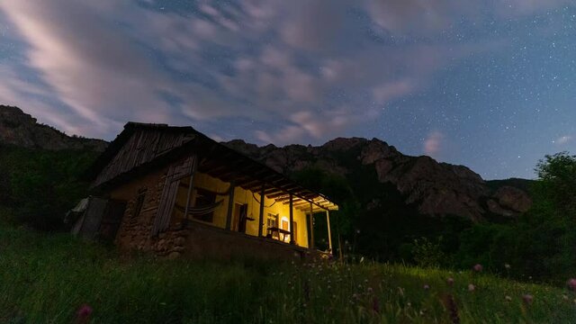 Moving clouds in night sky andromeda in milky way galaxy and starry night over a wild hut in Forest in Iran