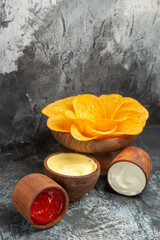 Vertical view of crispy potato chips decorated like flower shaped mayonnaise and ketchup on gray table