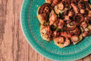 Turquoise plate with Galician octopus on a wooden table. Concept healty food.