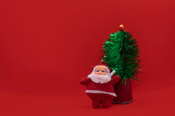 Christmas tree with Santa Claus on red studio background. Holiday festive celebration greeting card with copy space