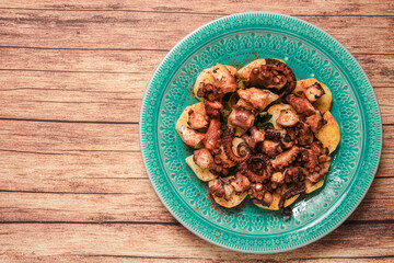 Turquoise plate with Galician octopus on a wooden table. Concept healty food.