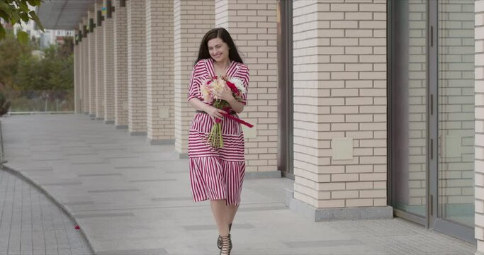 game in a chic striped dress happy goes after a date with a bouquet of flowers