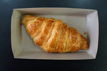 Freshly baked butter croissants on a takeaway paper plate in a pastry shop. Top view image.