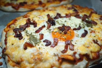 Pizza with bacon, melted cheese, olives, mushrooms and cherry tomatoes. Soft focus image.