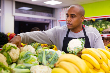 Man working in supermarket near vegetable section