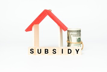 A picture of wooden block with subsidy word, house miniature and fake money insight. Property subsidy is one of the method to boost real estate  purchase during covid-19 pandemic.