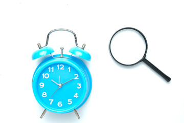 A picture of alarm clock and magnifying glass on white background.