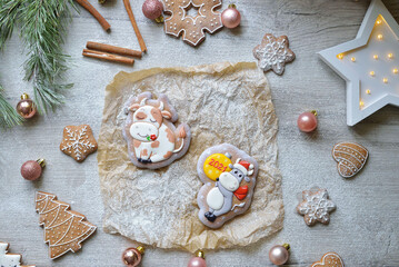 Fototapeta na wymiar two Christmas gingerbread in glaze in the form of bulls, Christmas symbols 2021, on a white table with New Year's decor, horizontal