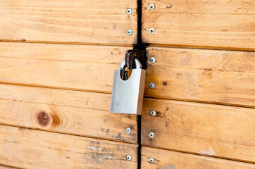 Closed padlock on a painted brown pine wooden door