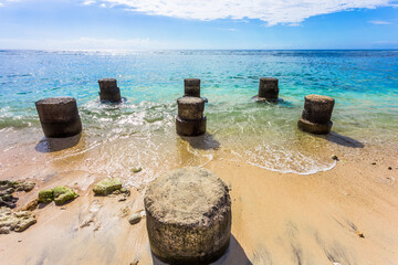 Naklejka premium Vestiges de piliers de ponton sur plage de Saint-Gilles-les-Bains, île de la Réunion 