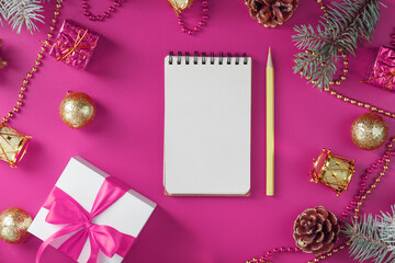 Clean white notepad with pencil around Christmas decorations on pink background. Planning