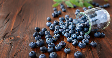 Glass jar of ripe blueberry with mint leaves Provence style wooden table.
