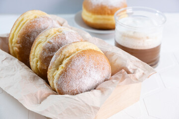 glass cup of coffee and doughnuts on wooden white background