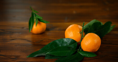 Tangerines with leaves on wooden table on brown background