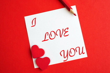 I love you written on a white sheet that lies on a red background. A declaration of love. Wedding and Valentine's Day