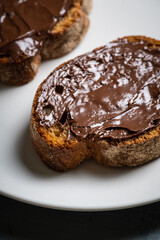 Slice of homemade bread with chocolate cream on the kitchen table for breakfast. Selective focus. Shallow depth of field.