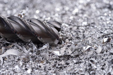 Silver end mill cutter with metal shavings. Processing of ferrous metals in a factory