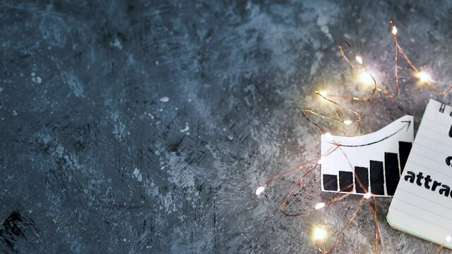 law of attraction notepad with text next to credit cards and positive stats surrounded by fairy lights
