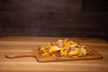 tasty french fries with bacon on wooden table