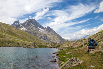 Fototapeta na wymiar Man Sitting next to a High Alpine Lake in the Col d'Arsine in the Parc des Ecrins, Department Haute Alps, France