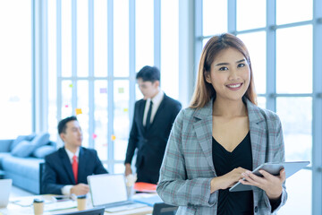 Beautiful young secretary is using a tablet in a meeting with management.