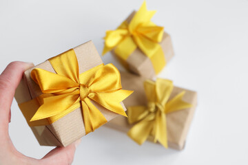 Tree gift boxes wrapped by kraft brown paper with beautiful yellow satin ribbons on ultimate gray background. Universal gifts design for all kind of celebration