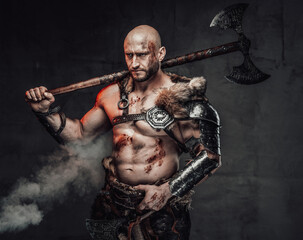 Portrait of a furious viking warrior with grimy and bloody skin in light armour in dark smokey...