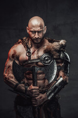 Serious and furious scandinavian barbarian with bald head and grimy and bloody skin in armour with...