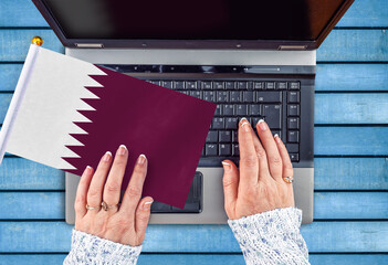 woman hands and flag of Qatar on computer, laptop keyboard 