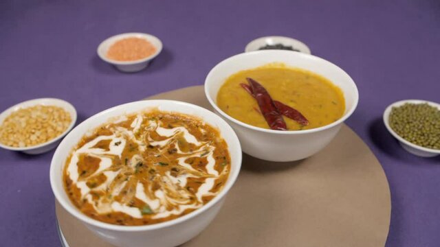 Freshly prepared garnished Dal fry / Tadka and Dal Makhani kept on a rotating table - Indian Food. Raw lentils (Moong  Masoor  Arhar  and Urad) placed with famous traditional Indian Dal dishes agai...