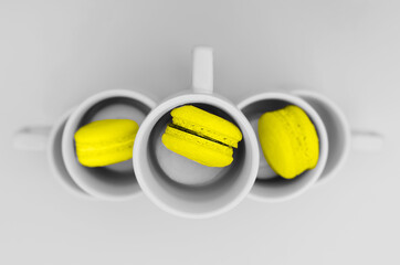 Yellow macaroons with plates on a gray background. Fashionable color combination. Trending color combinations of 2021.