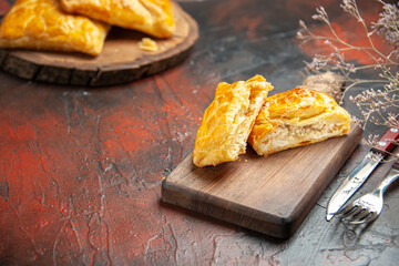 bottom view penovani khachapuri on wood board and on chopping board knife and fork on dark red table free space