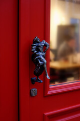Fototapeta na wymiar Vintage door handle in the form of a man on a red door