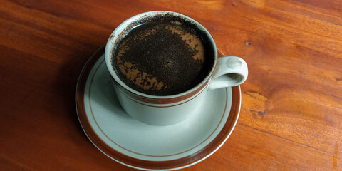Brewed coffee or (tubruk coffee) with extra milk on a wooden table