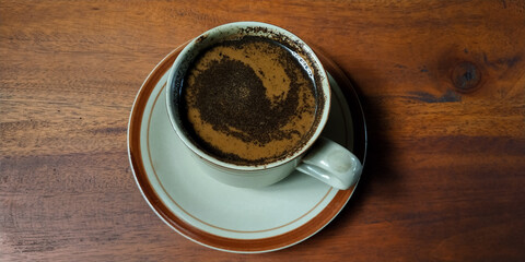 Brewed coffee or (tubruk coffee) with extra milk on a wooden table