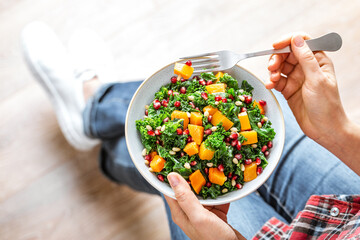 Vegetable salad bowl in woman hands. Fresh kale and baked pumpkin salad. Healthy eating concept