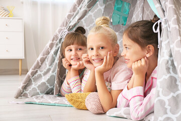 Cute little girls lying in wigwam at home