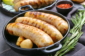 Pan with delicious grilled sausages and spices on dark background