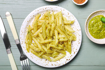 Plate with tasty pasta and pesto sauce on color background