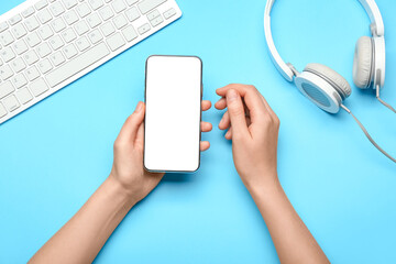 Hands with mobile phone and headphones at workplace