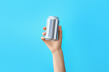 Hand with metal can on color background