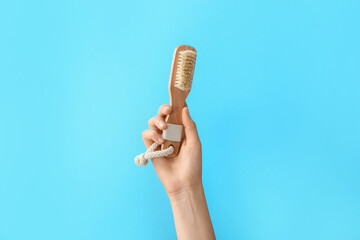 Hand with massage brush on color background