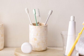 Holder with toothbrushes and toothpaste on table in bathroom