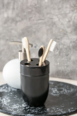 Holder with wooden toothbrushes on table in bathroom