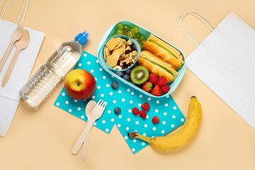 School lunch box with sandwiches, vegetables and fruits on orange background.