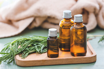 Bottles with rosemary essential oil on table