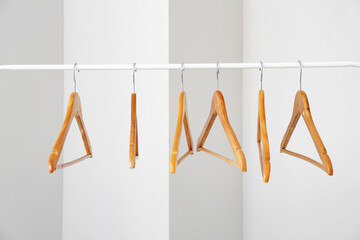 Rack with clothes hangers on light background