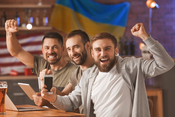 Happy men after winning of their sports bets in pub