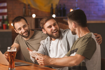 Happy men after winning of their sports bets in pub